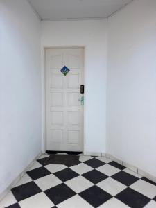 a room with a white door and a checkered floor at Flat Jubarte Praia do Francês in Marechal Deodoro