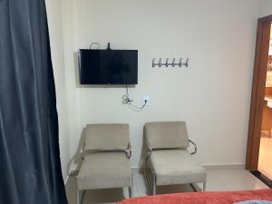 two chairs in a room with a tv on a wall at Chalé 3 vista para montanha in Itatiaia