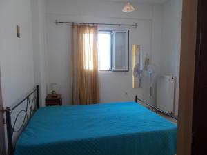 a bedroom with a blue bed with a window at Διαμέρισμα τριών ατόμων in Filiatra +21 photos