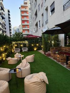 a garden with white chairs and tables on the grass at Santa5 hostel in Vlorë