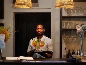 a man holding a tray with two cocktails on it at Addo African Home in Addo