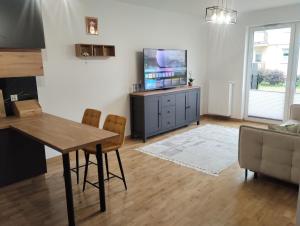 a living room with a table and a flat screen tv at Nowoczesny Apartament 400 M Od Plaży Prywatny Ogródek Ełk in Ełk