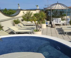 a swimming pool with chairs and an umbrella on a patio at Hotel Enrichetta in Desenzano del Garda