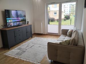 a living room with a couch and a flat screen tv at Nowoczesny Apartament 400 M Od Plaży Prywatny Ogródek Ełk in Ełk +9 photos