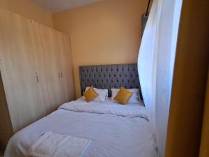 a small bedroom with a bed with yellow pillows at Utele Cottages in Thika