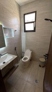 a bathroom with a toilet and a sink and a window at شقة انيقة بغرفة وصالة in Buraydah
