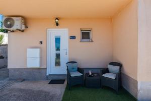 a patio with two chairs and a table and a door at Apartman Hana u blizini ronilačkog kluba i Kostrenskih plaža in Kostrena