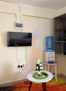 a room with a table and a tv on a wall at Tulivu House in Embu