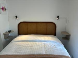 a bed in a bedroom with two lights on the wall at Hôtel de Provence in Cannes