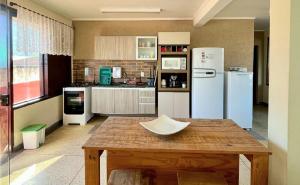 a kitchen with white appliances and a wooden table at Apartamento Vista ao Mar Maresias in Maresias