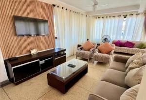 a living room with a couch and a flat screen tv at Apartamento Vista ao Mar Maresias in Maresias