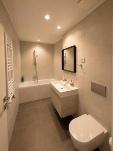 a bathroom with a toilet and a sink and a tub at Aria Lux Belgrade Waterfront in Belgrade +5 photos