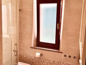 a bathroom with a window and a shower with a toilet at Casetta IV Vico- Chianalea in Scilla +10 photos