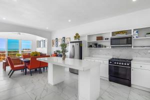 a kitchen with white cabinets and a table and chairs at Dog-friendly Home with Partial Ocean View, Heated Pool, Rooftop Terrace in Rosarito