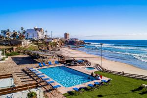 a swimming pool next to a beach and the ocean at Dog-friendly home 3 rows to beach with rooftop deck, pool, hot tub, & kitchen in Rosarito