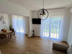 a living room with a table and chairs and windows at Villa La Lana in Mostar