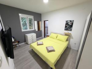a bedroom with a yellow bed and a television at Home Two Brothers in Bar