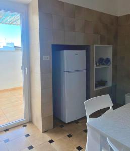 a white refrigerator in a kitchen with a table and a window at Casa di Lucy in Racale +14 photos