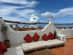 a white couch with four red pillows on a balcony at Tiri Hub in Tamraght Ouzdar