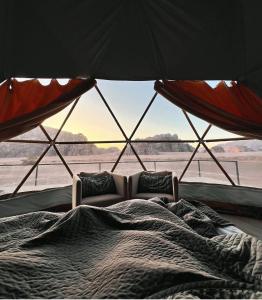 a bed in a tent with a large window at Ain Rum Luxury Camp in Wadi Rum