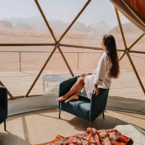 a woman sitting in a chair looking out at the desert at Ain Rum Luxury Camp in Wadi Rum