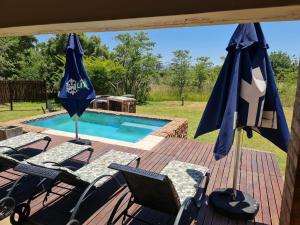 a deck with chairs and umbrellas next to a swimming pool at Sweet Zebula in Mabula