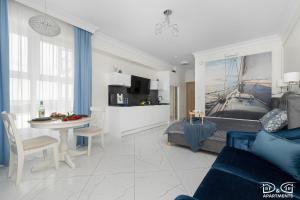 a living room with a blue couch and a table at Marítimo D&D Apartments Porta Mare in Dziwnówek
