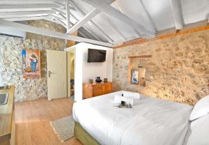 a bedroom with a white bed and a stone wall at Melias Olive Retreat in Kelefá