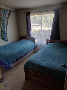 a bedroom with two beds and a window at Cabaña Ecologica Huinganes in Machalí