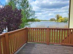 a wooden deck with a view of a lake at Dom Na Fali in Pasym