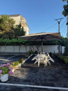 a patio with a table and an umbrella and flowers at Hotel De La Playa in Velipojë
