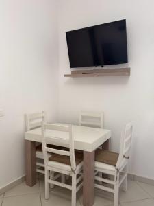 a dining room table with two chairs and a tv on the wall at Hotel De La Playa in Velipojë