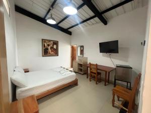 a bedroom with a bed and a desk and a television at Hotel Cerro Bravo in Fredonia