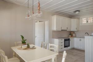 a white kitchen with a white table and chairs at Fiscardo View Villas in Fiskardo