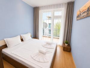 a bedroom with a large white bed with a window at Sunny Day 3 - Pool and Chill in Sunny Beach +12 photos