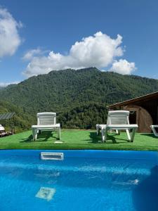 two white chairs sitting next to a swimming pool at Mtirala Yurt in Batumi