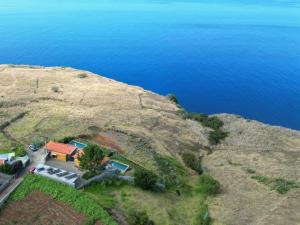 an aerial view of a house on a hill next to the water at Villa Flora Calheta Sunset & Ocean Views in Jardim do Mar