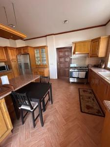 a kitchen with wooden cabinets and a black table and chairs at Horizon 3 Villa in Amman