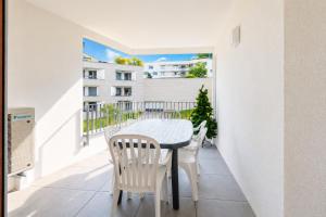 a table and chairs on the balcony of a apartment at Lac arte postale- Terrasse, grand garage privatif, borne de recharge en électricité, climatisation murale un appareil dans chaque pièce et unité extérieure, lit-parapluie pour bébé possible in Annecy