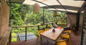 a wooden table and chairs on a balcony with a view at River House superbe vue- vue et accès directe sur la rivière et baignade dans les bassins naturels in Saint-Joseph