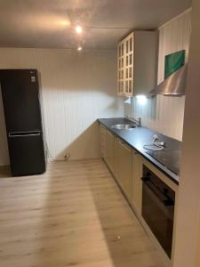 a kitchen with a black refrigerator and a sink at Modern basement apartment, 65 square meters in Alta +3 photos