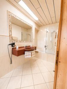 a bathroom with a sink and a shower and a mirror at Hotel Bechlwirt in Kirchberg in Tirol +40 photos
