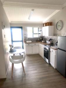 a kitchen with white cabinets and a table and a chair at Living Lite 1 and 2 in Kleinmond