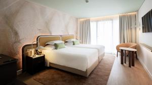 a bedroom with a large white bed and a window at Sao Miguel Park Hotel in Ponta Delgada