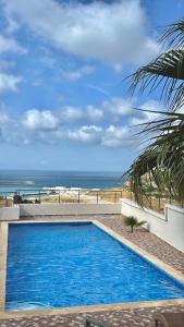 a blue swimming pool with the ocean in the background at zahara appartement in Tangier