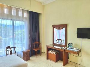 ein Hotelzimmer mit einem Bett und einem Schreibtisch mit Spiegel in der Unterkunft Hotel Caredek in Solok