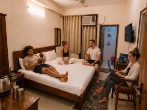 a group of people sitting on a bed in a room at Cozy Den in Jaipur