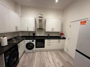 a kitchen with white cabinets and a washer and dryer at Catherine Lodge Finchley in Whetstone +15 photos