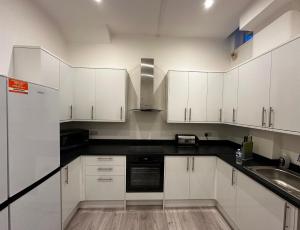 a kitchen with white cabinets and a sink at Catherine Lodge Finchley in Whetstone
