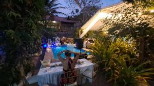a woman sitting at a table in front of a pool at night at Hotel Sumpa in Montañita